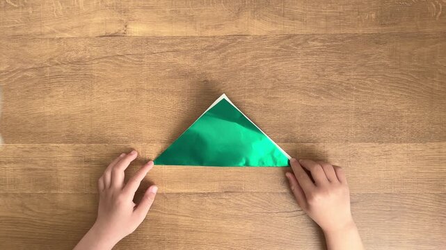 child hands adjusting misaligned green origami triangle slow motion 4K