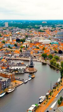 Vertical video. Haarlem, Netherlands. Windmill De Adriaan (1779). Windmill from the 18th century. Panoramic view of Haarlem city center. Cloudy weather during the day. Summer. Drone footage. Rich col
