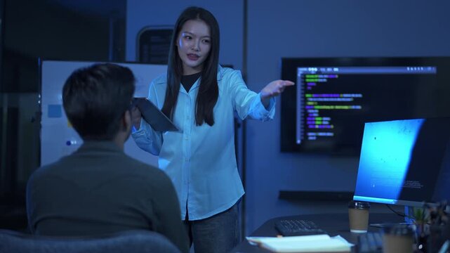 Professional female software developer holding a tablet and presenting system architecture and code development progress to a stakeholder in a modern office.