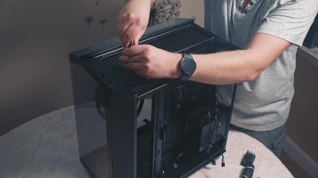 Securing top ventilation panel of computer case with screws using screwdriver during final stage of desktop PC assembly