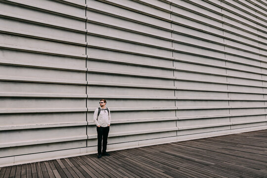 Minimalist urban scene with a lone man leaning against a ribbed wall