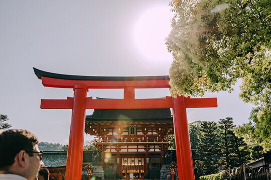 Red torii gate at japanese shrine with sun flare