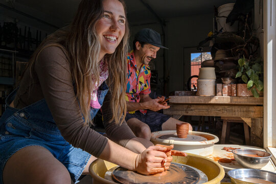 Young female and male spinning pottery in window light