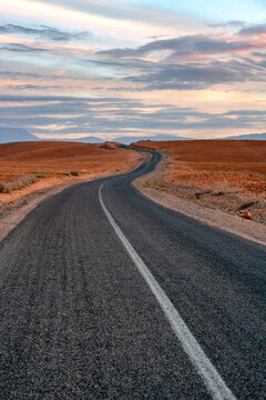 Winding asphalt road through an empty desert landscape in Morocco