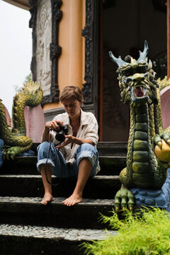 Young woman photographer reviewing shots at Buddhist monastery, Bali