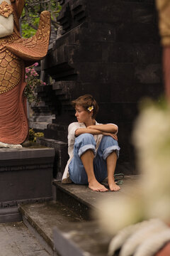 Solitary woman sitting on steps of Hindu temple, Bali, Indonesia