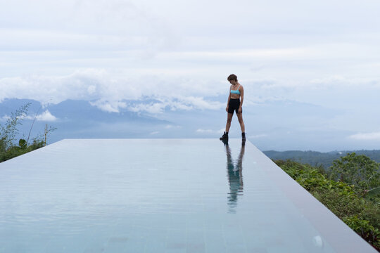 Athletic woman at hilltop infinity pool surrounded by jungle, Bali