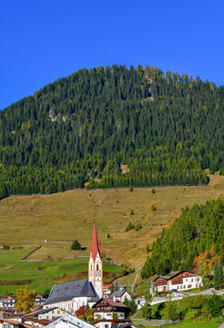 Pfarrkirche St. Valentin vor bewaldetem Berghang in Nauders am Reschenpass, Tirol