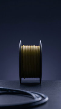 Tall vertical composition emphasizing pure geometric form with a professional optical fiber distribution spool, showing tightly wound rows of yellow buffer tubes in silhouette beams.
