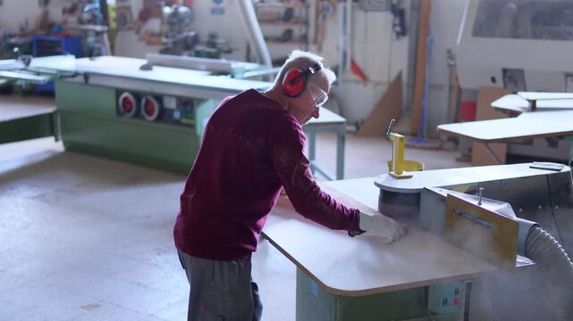 Professional carpenter sanding wood on a belt sander