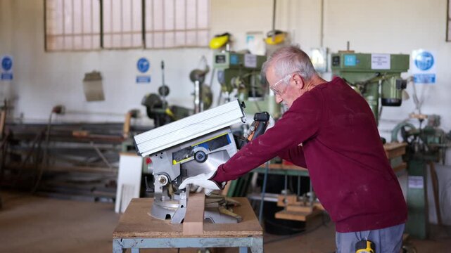 Senior carpenter cutting wood with miter saw