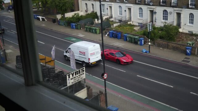 Street-level footage capturing a suburban area in London, England. The scene features residential streets, houses, parked cars, and everyday neighborhood surroundings.