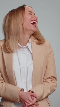 Amused office secretary woman pointing finger to camera, laughing out loud, taunting making fun of ridiculous appearance, funny joke anecdote. Business lady isolated alone on gray studio background