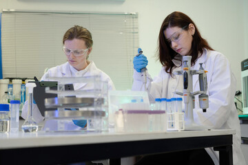 Fototapeta premium Two Female Scientists Working in Modern Research Laboratory with Pipette and Lab Equipment