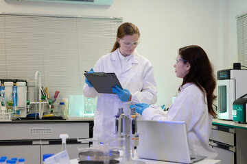 Naklejka premium Two Female Scientists Collaborating in Modern Research Laboratory with Equipment and Clipboard
