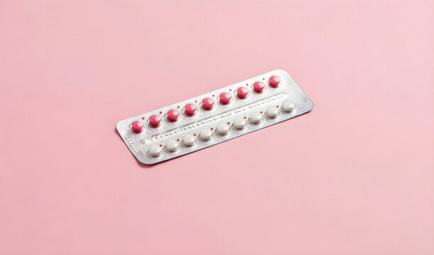 Pink blister pack with white oral contraceptive pills on pink background, banner poster for women&rsquo;s health contraception family planning and reproductive medicine awareness with copyspace.