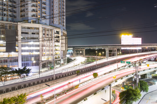 Long exposure night shot of Magallanes Flyover with traffic light trails painted across the highway, Makati, Philippines