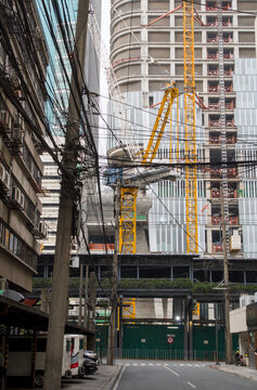 Urban jungle cityscape with a construction site and tangled electrical wires like vines on a city street