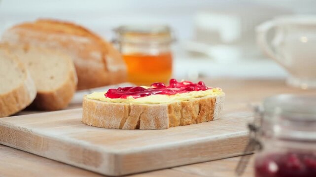 Butter and jam spreading on fresh bread slice close up homemade breakfast, copy space