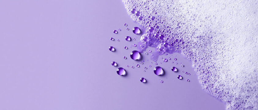 Close-up abstract background featuring white soap foam and clear water droplets on a smooth pastel purple surface, ideal for beauty, skincare, and hygiene product concepts with copy space.