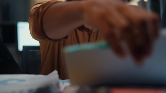 Close up overworked young Latin businessman working late on document in large stack of paper files at office night. Tax audit deadline, accounting stress, corporate burnout, urgent business concept.