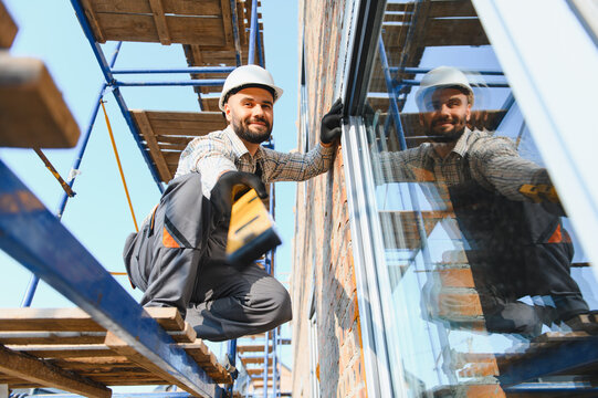 Construction worker installing window on building facade
