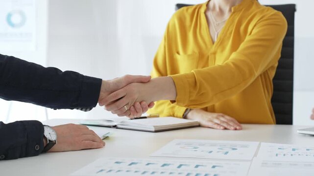 Professional businesspeople shaking hands, confirming partnership agreement in contemporary corporate workspace