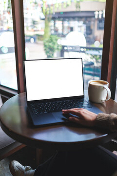 Vertical mockup image of a woman working on laptop computer with blank white desktop screen in cafe