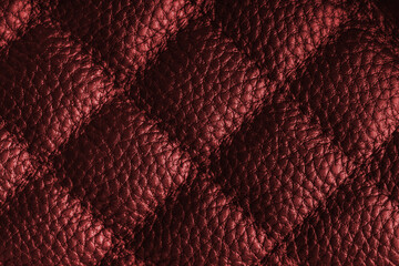 Fototapeta premium Close up, macro of red quilted leather texture with stitched diamond pattern, luxury material surface shining metal effect for fashion, upholstery or design wallpaper, rough, relief background