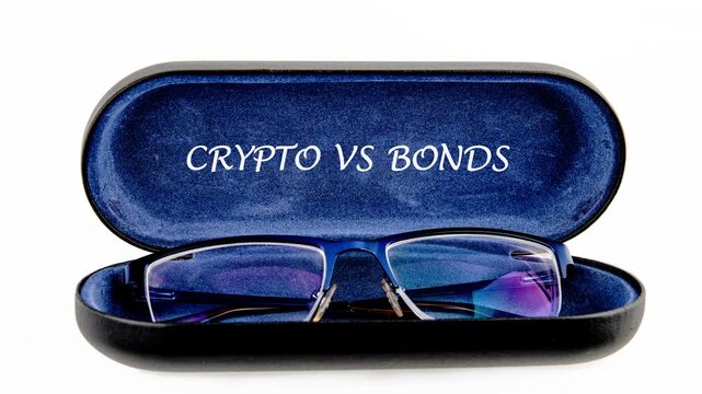 Blue framed eyeglasses are neatly placed in an open dark blue velvet case. The phrase Crypto Versus Bonds is visible on the cases inner lid, symbolizing investment concepts