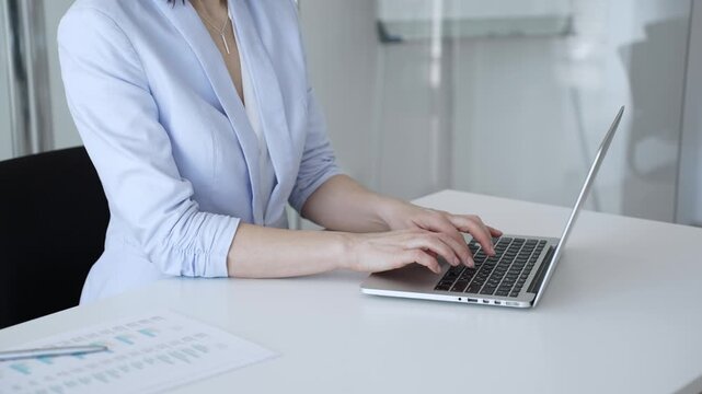 Businesswoman's hands typing on a laptop, performing data entry, communicating via email, or engaging in a productive online task at an office desk, highlighting focus and efficiency
