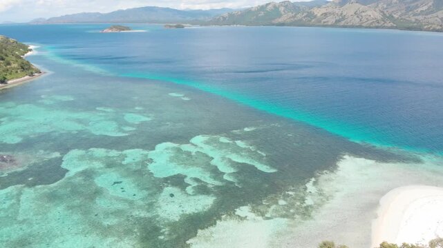 Panoramic aerial view of the 17 Islands Marine Park near Riung, Flores, Indonesia, featuring turquoise coral reefs, tropical islets, and deep blue ocean under a bright sky