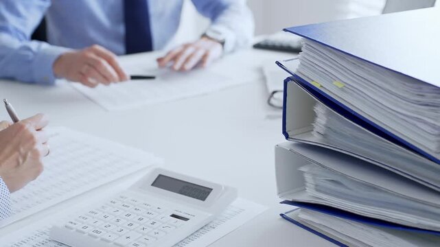 Accountants collaborating on financial reports and strategies while calculating and verifying documents in an office setting. Audit and taxes in business