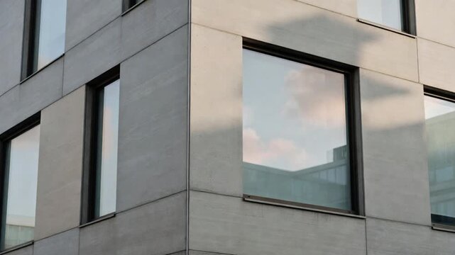 Modern Minimalist Building Facade with Concrete Panels and Sky Reflections in Windows