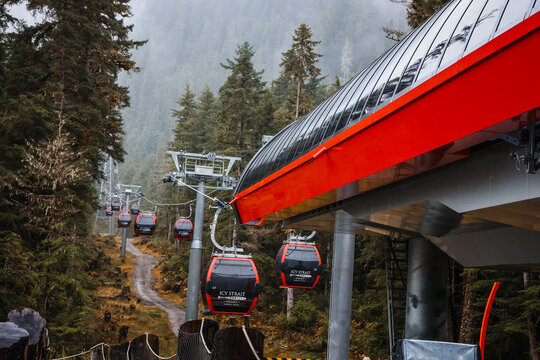Icy Strait Point, Alaska - September 20, 2025: Red Sky Peak Gondola cabins moving up a misty mountain mountain through a pine forest in Hoonah.