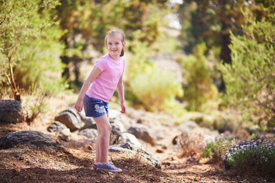 Little girl standing among rocks and trees in the pine forest of Las Lajas in Tenerife, Canary Islands, Spain.