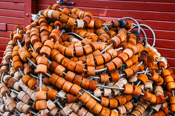 Close Up of Weathered Orange Fishing Net Floats Piled Against a Red Wooden Wall in Alaska © AJITH.A
