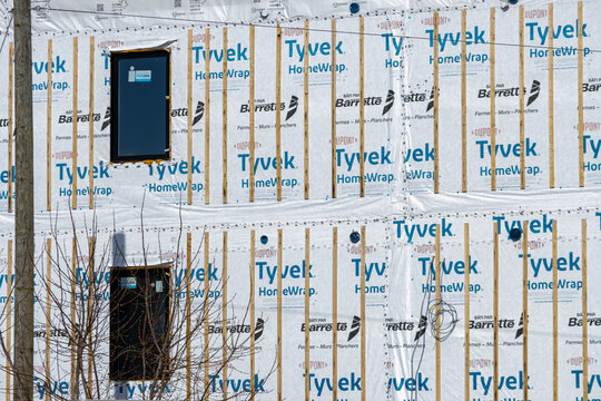 Quebec, Canada, 24 April 2026 : A residential building under construction features Dupont Tyvek HomeWrap and Barrette wood framing with installed windows.