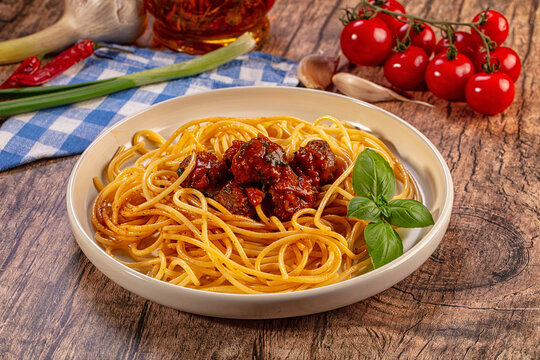 Spaghetti meatballs, fresh basil, cherry tomatoes, garlic, chili pepper, wooden table background