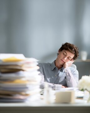 lazy office employee procrastinating at messy desk work burnout concept