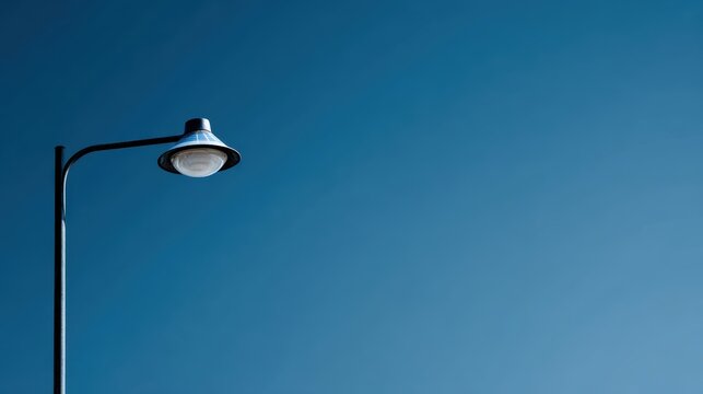 Solar street light with LED lamp and solar panel standing against blue sky, renewable energy lighting for roads and parks