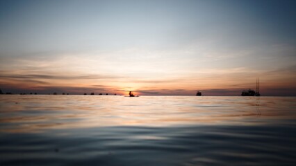 Fototapeta premium Paddleboarder relaxing on the water during a vibrant colorful sunset at sea