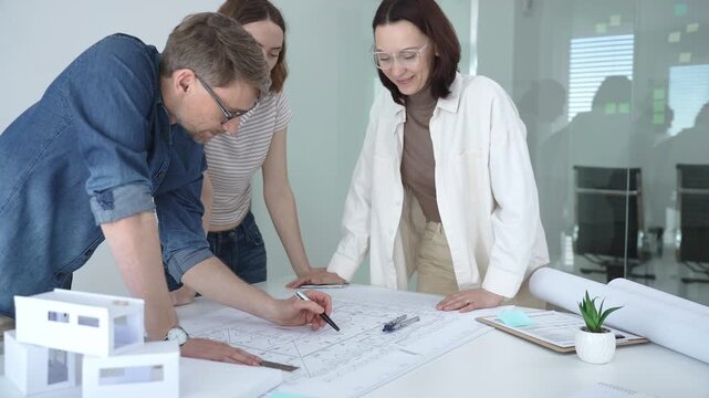 Architects and urban planners are working together, analyzing building plans and creating a small scale architectural model for a new residential or commercial project