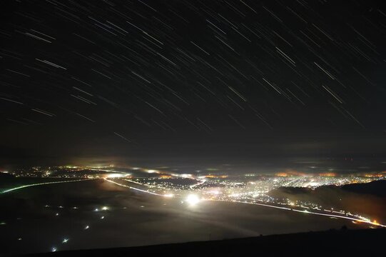 雲海と夜景の上に広がる星の軌跡とタイムラプス風景
