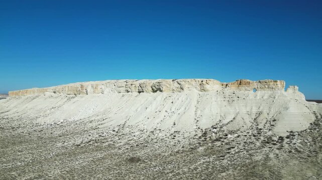 Drone flight over a lonely white chalk rock standing amidst the barren desert terrain of Mangystau. Wild nature, Martian landscapes, unique geology of Kazakhstan, arid climate, limestone formations