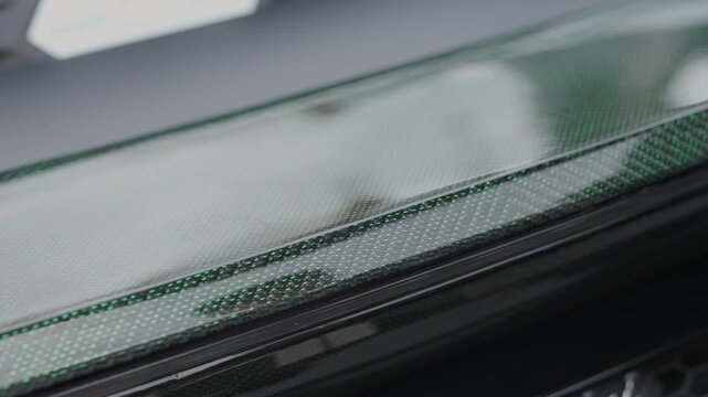 Cinematic close-up of glossy green carbon fiber texture on supercar.