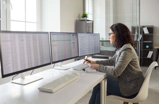 Accountant analyst works on computer monitors spreadsheets. In an office, the woman auditor reconciles finance, checks data quality, and runs analytics. Business accuracy and control concept.
