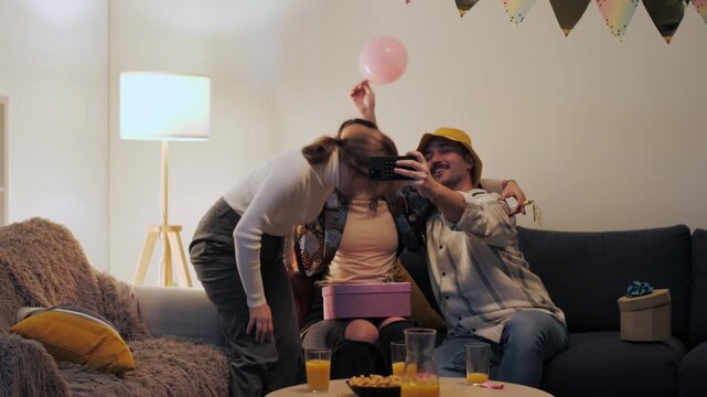 Joyful friends taking selfies at birthday party