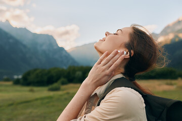 Fototapeta premium A woman enjoys the outdoors in a mountain landscape, head tilted back to feel the breeze in bright open air. A serene moment of nature, calm and breathing freely.