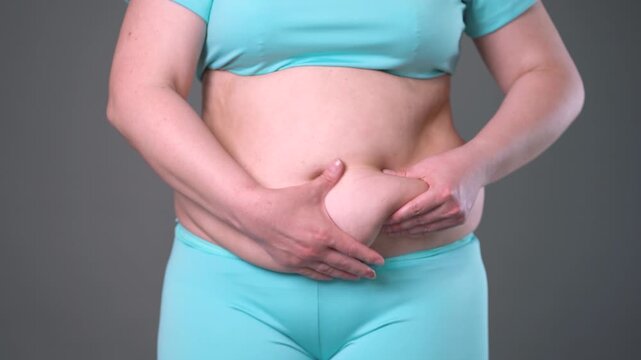 Overweight woman massaging belly fat, stomach self-massage. Weight loss, diet and anti-cellulite body care concept